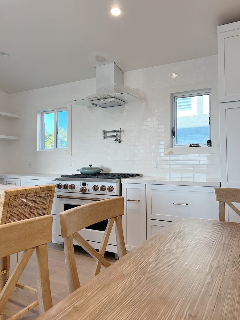 New beach house kitchen. White kitchen with white tile, quarts island, appliances, wood table and white cabinets.