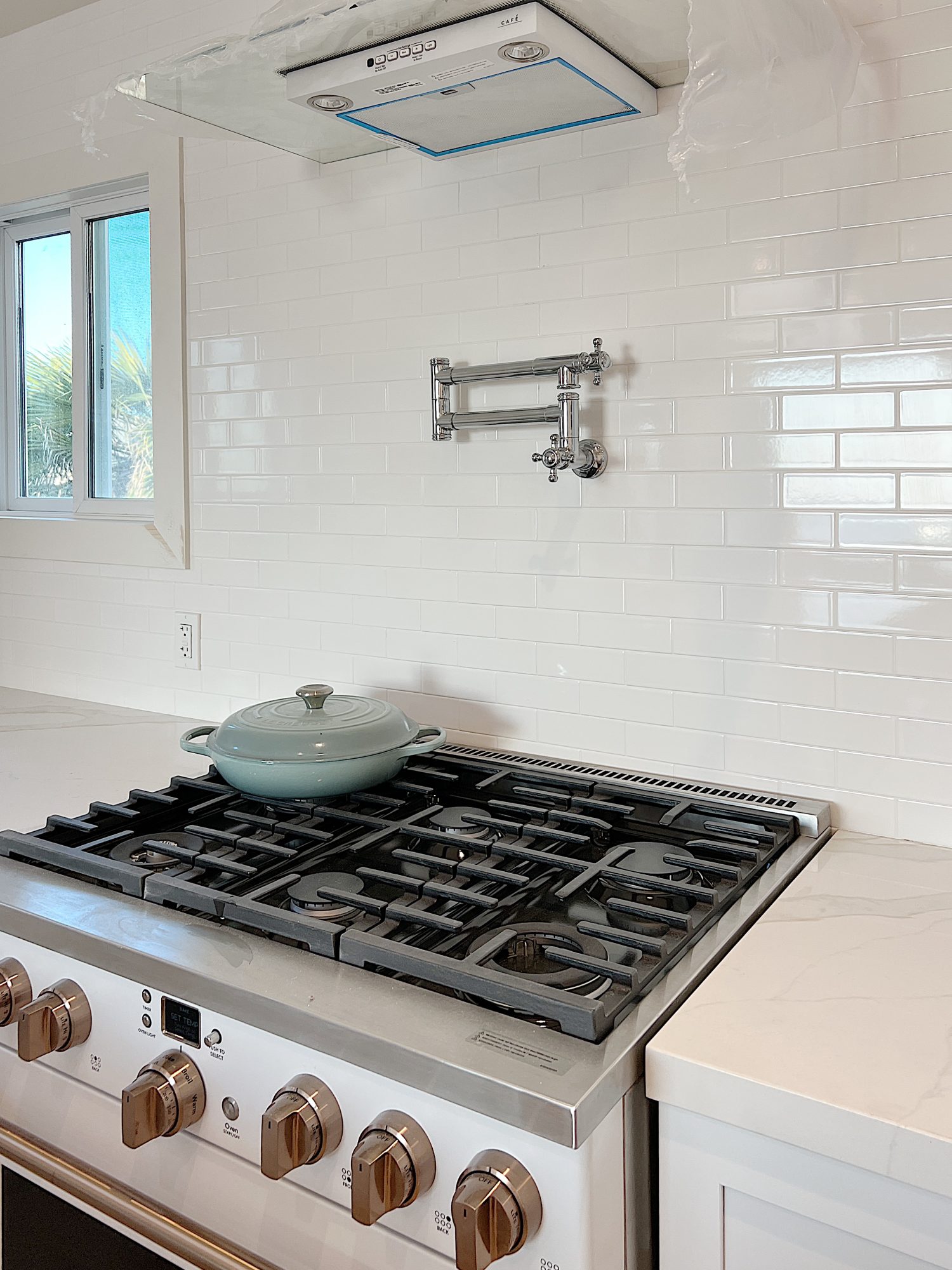 New beach house kitchen. White kitchen with new white stove, pot filler, white tile, quarts island, appliances, wood table and white cabinets.