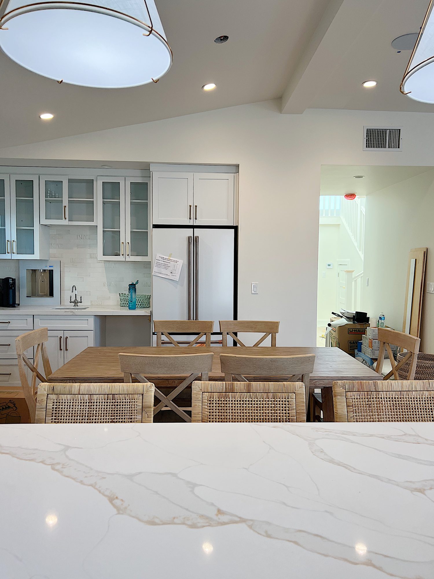 New beach house kitchen. White kitchen with white tile, quarts island, appliances, wood table and white cabinets.