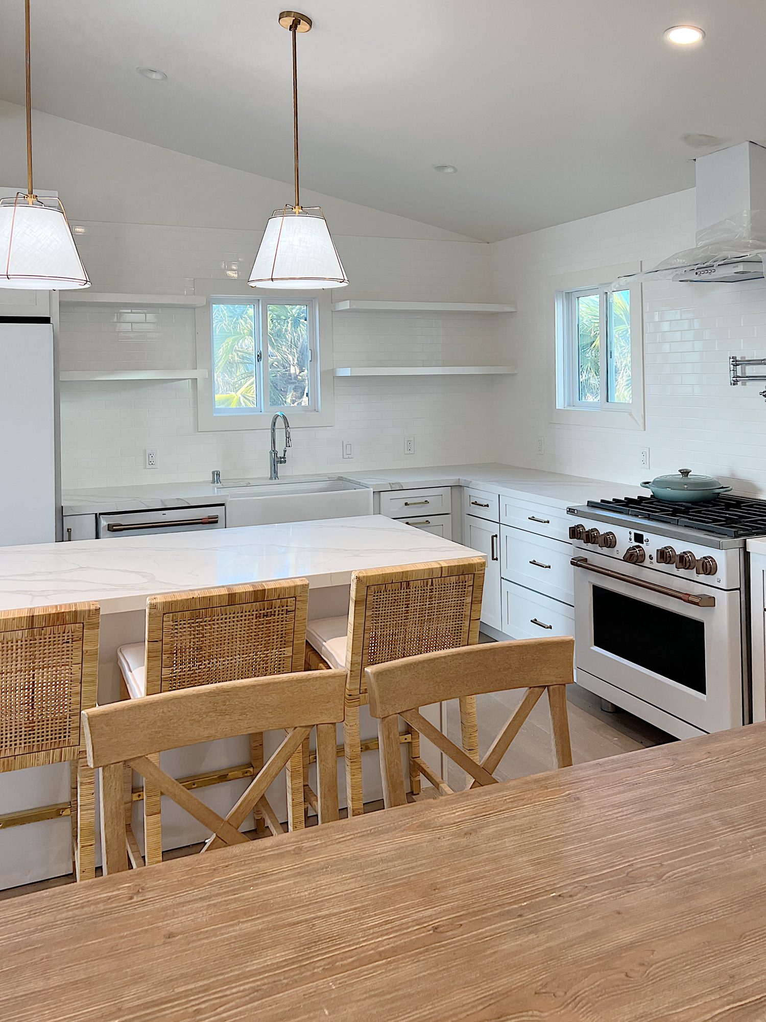 New beach house kitchen. White kitchen with white tile, quarts island, appliances, wood table and white cabinets.