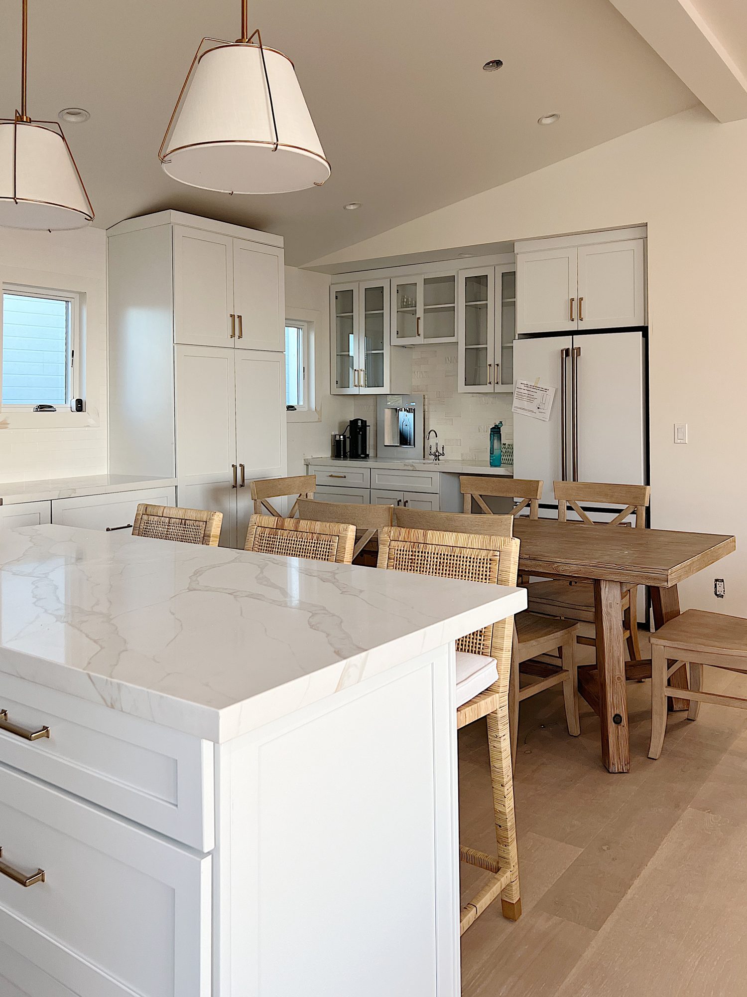 New beach house kitchen. White kitchen with white tile, quarts island, appliances, wood table and white cabinets.