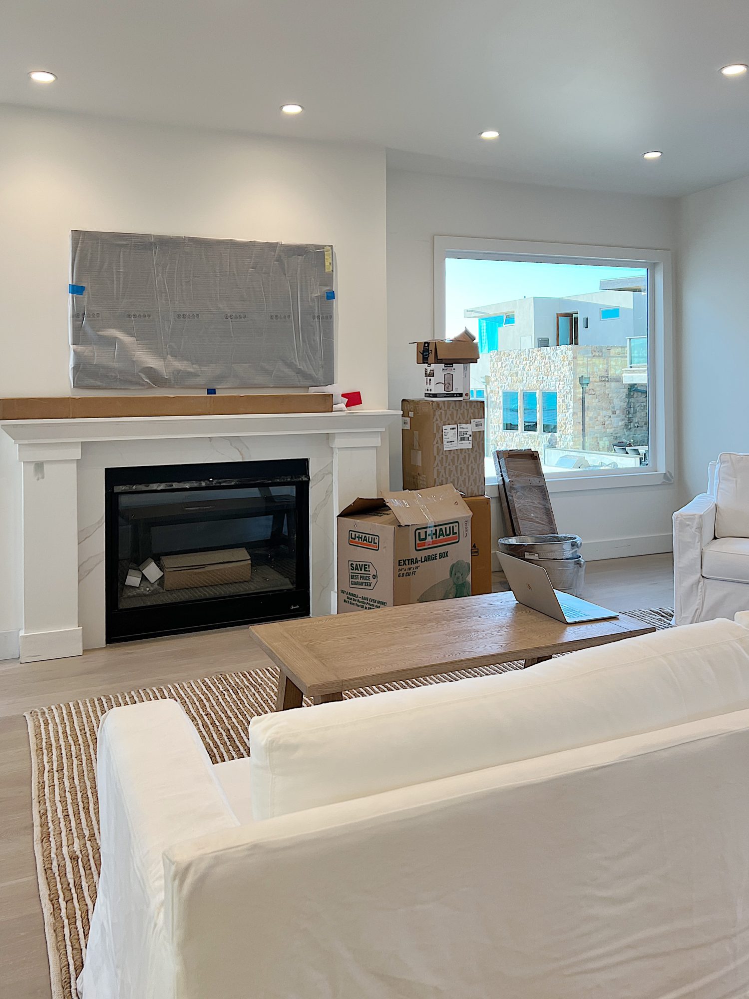 Living area of the newly remodeled beach house with fireplace, TV, coffee table, rug and white sofa.