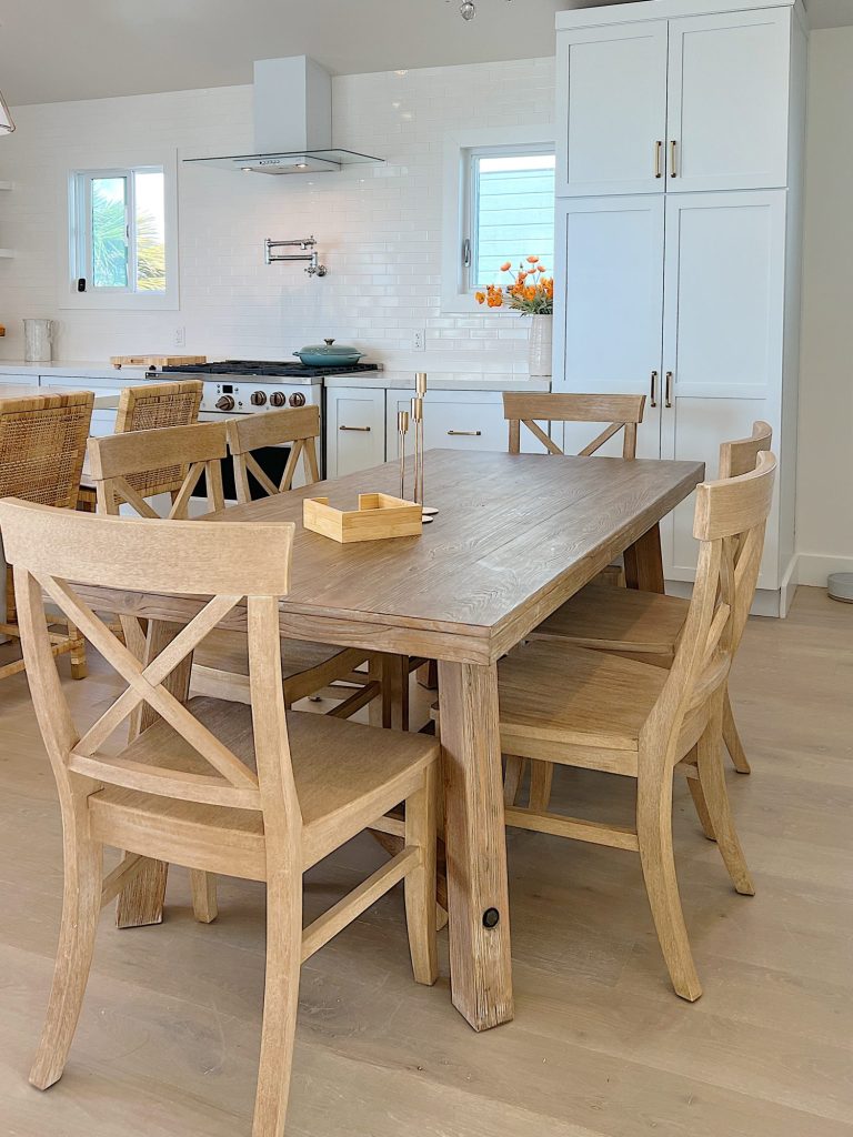Wood kitchen table and chairs in a white kitchen with white cabinets and appliances