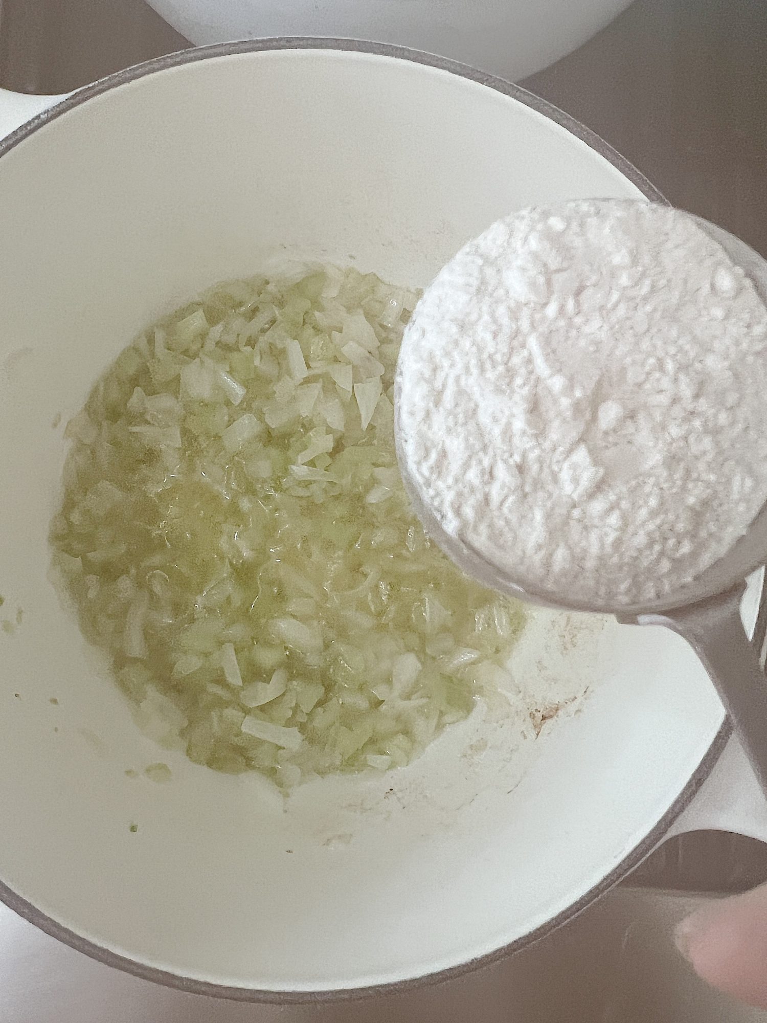 adding flour to a saucepan of cooked onions, celery, and butter