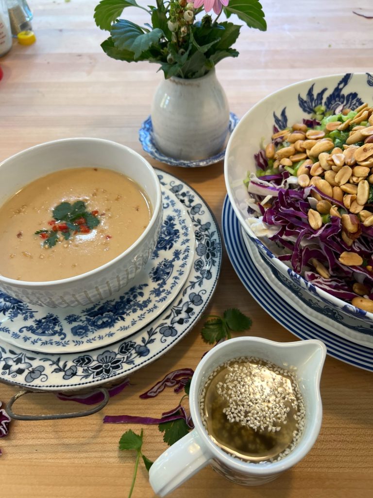 A peanut soup in a blue and white bowl and a peanut crunchy peanut coleslaw with a vinaigrette dressing.