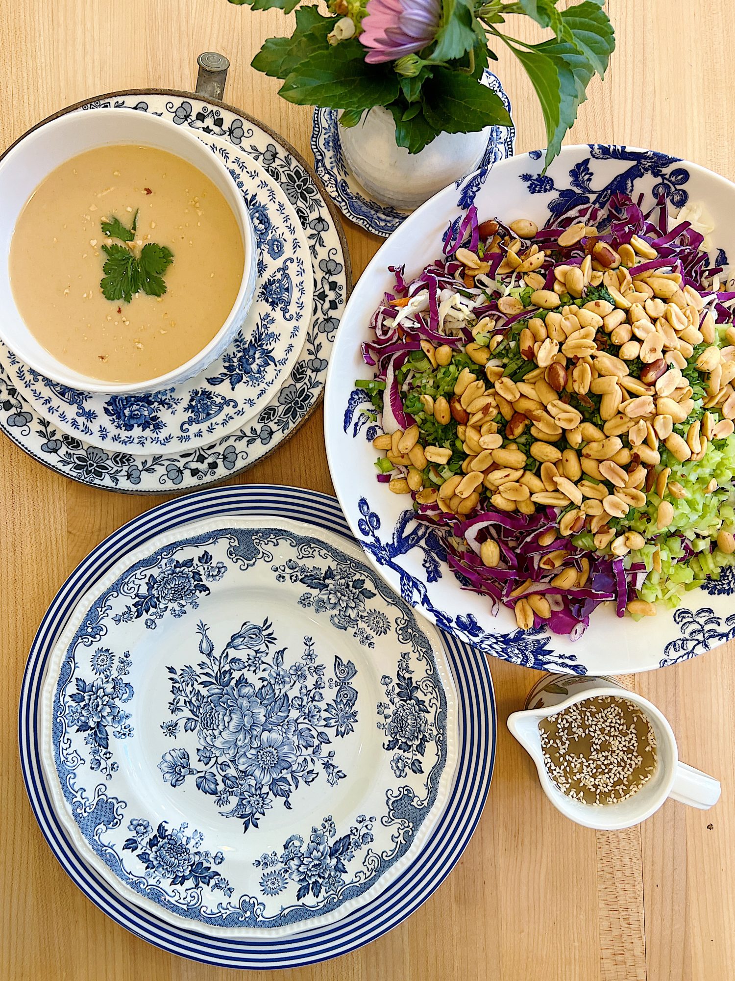 A peanut soup in a blue and white bowl and a peanut crunchy peanut coleslaw with a vinaigrette dressing.