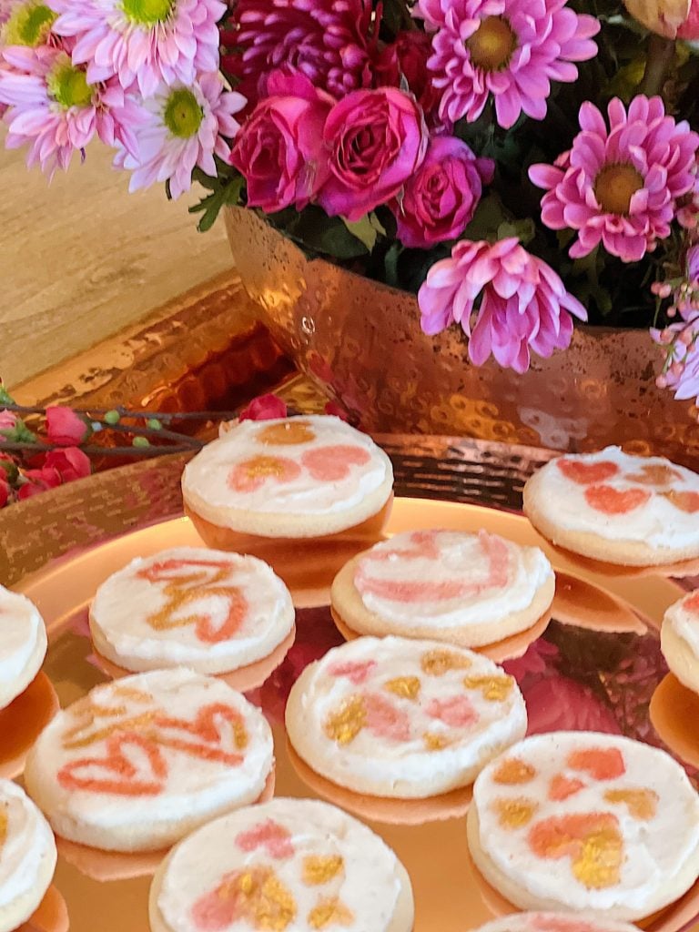 Valentine Cookies Decorated with Edible Luster Dust on a copper plate with fresh flowers in a copper bowl.