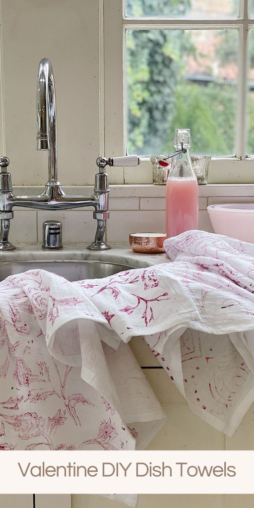 Handprinted pink and white dish towels sitting on a kitchen sink with pink dish soap in a bottle.