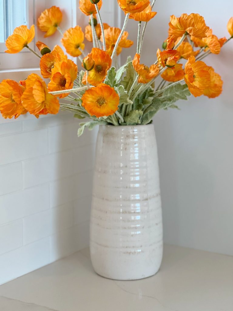 faux orange poppy flowers in a white ceramic vase