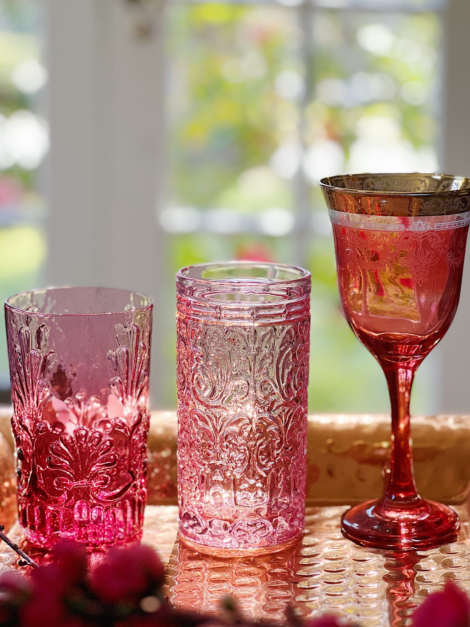 three pink glasses, one with a gold rim, one with texture and one that is original cranberry glass.