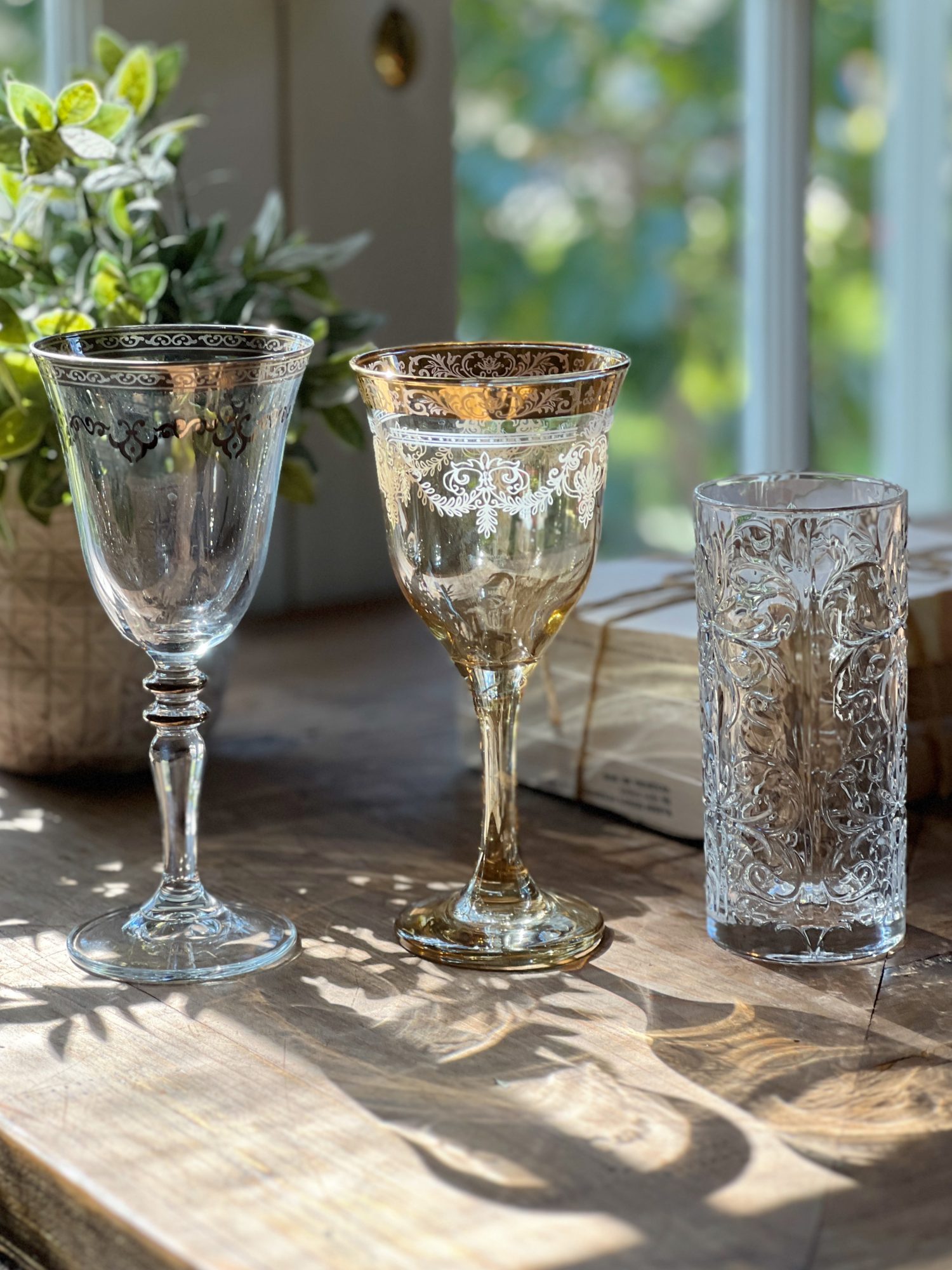 three clear glasses with silver and gold etching.