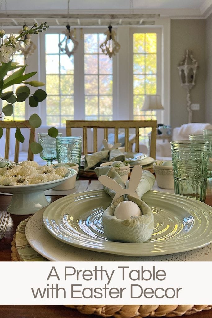 An Easter table with sage green plates and decor and cloth napkins folder with bunny ears.