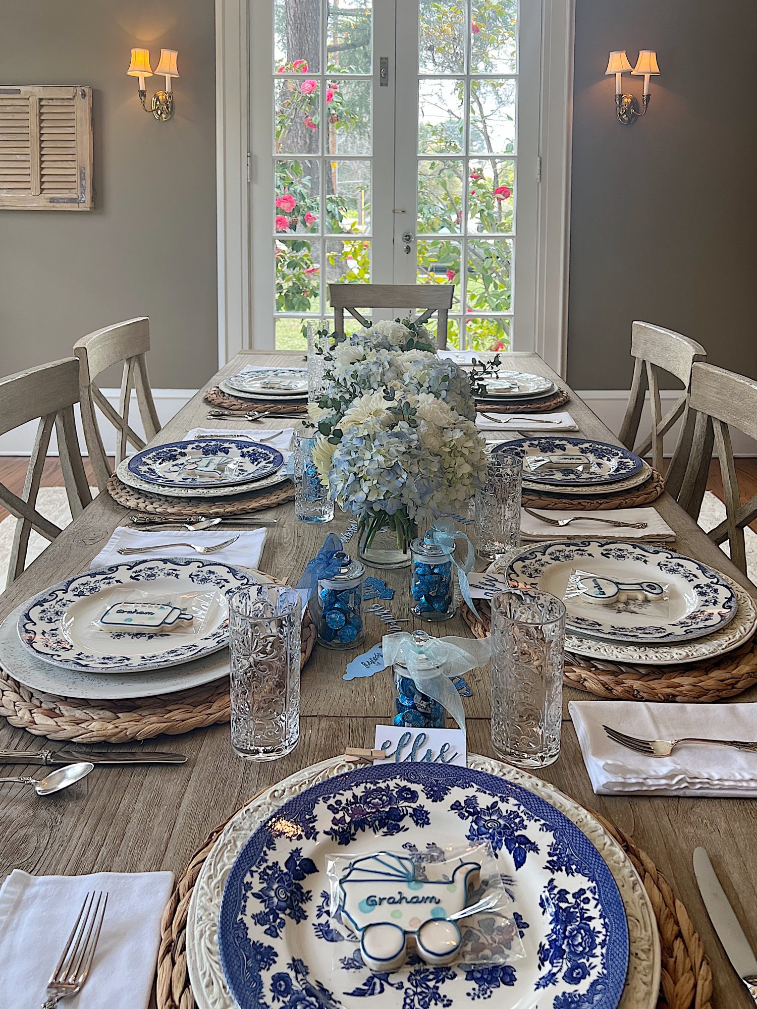 Dining table for a baby shower with blue and white plates, flowers, and babythemed decorations.