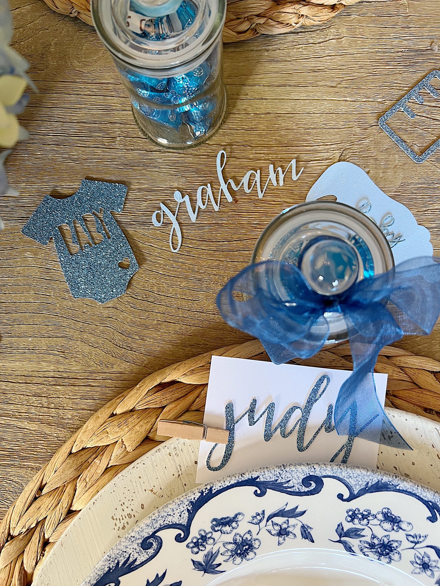 Dining table for a baby shower with blue and white plates, flowers, and babythemed decorations.