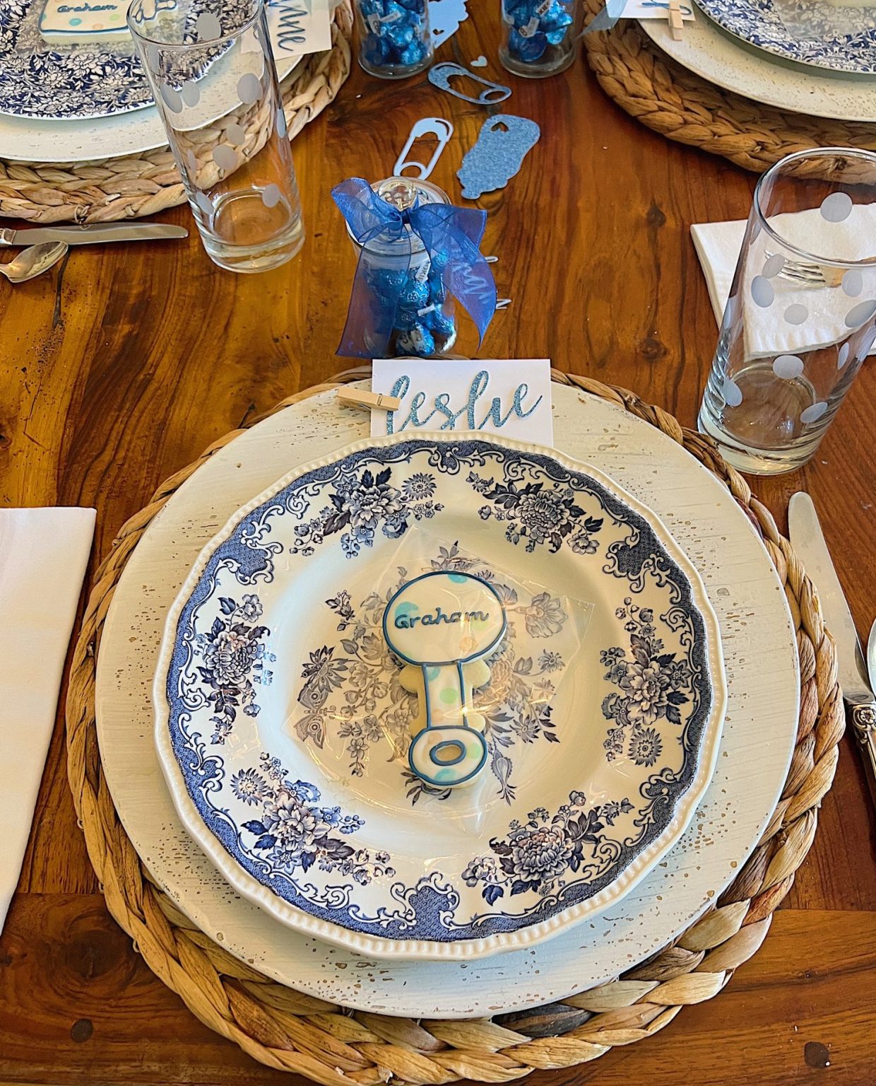 Dining table for a baby shower with blue and white plates, flowers, and babythemed decorations.