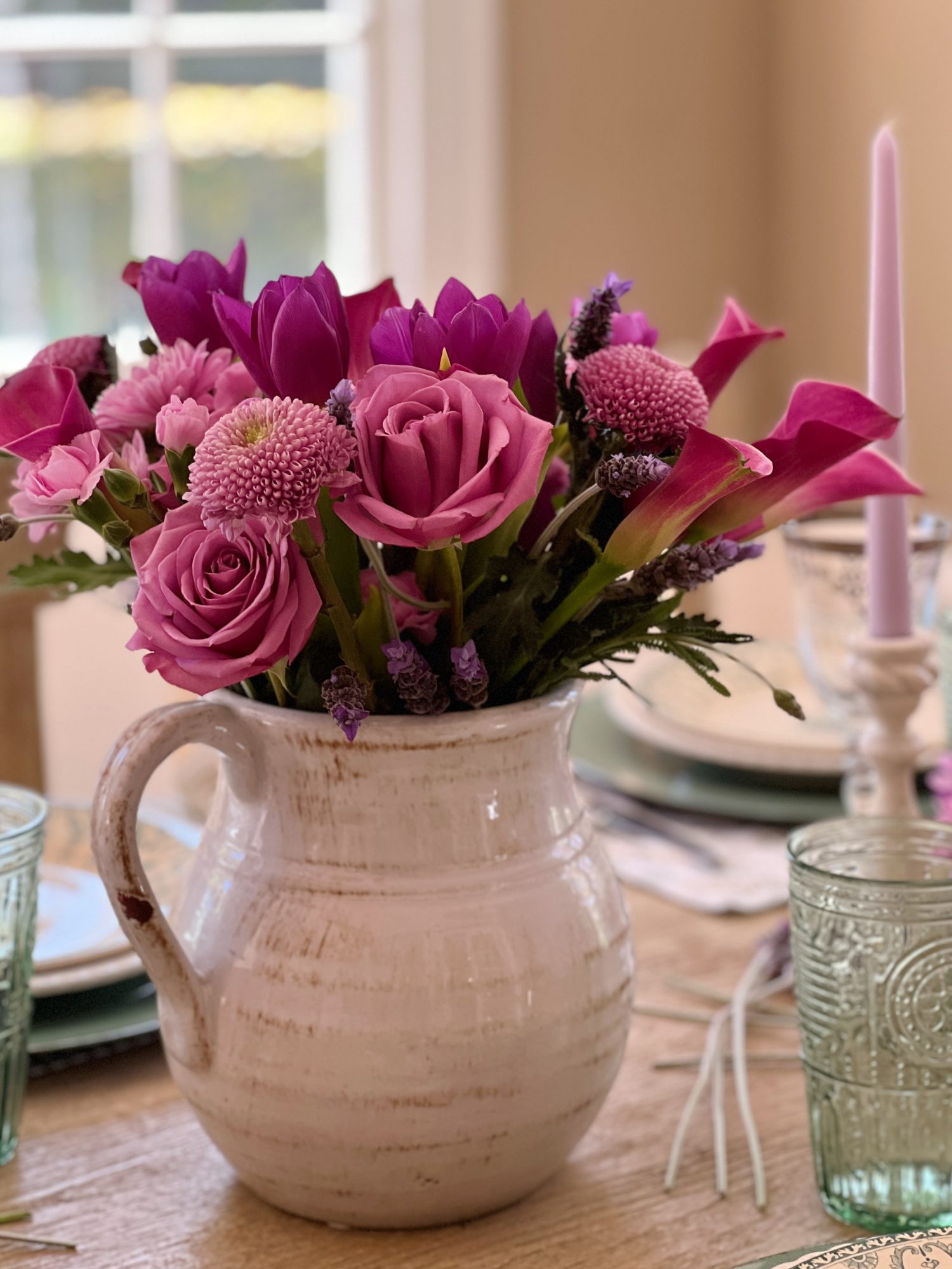 A spring table set in the dining room with green and white plates and napkins, lavender ties, green and sil