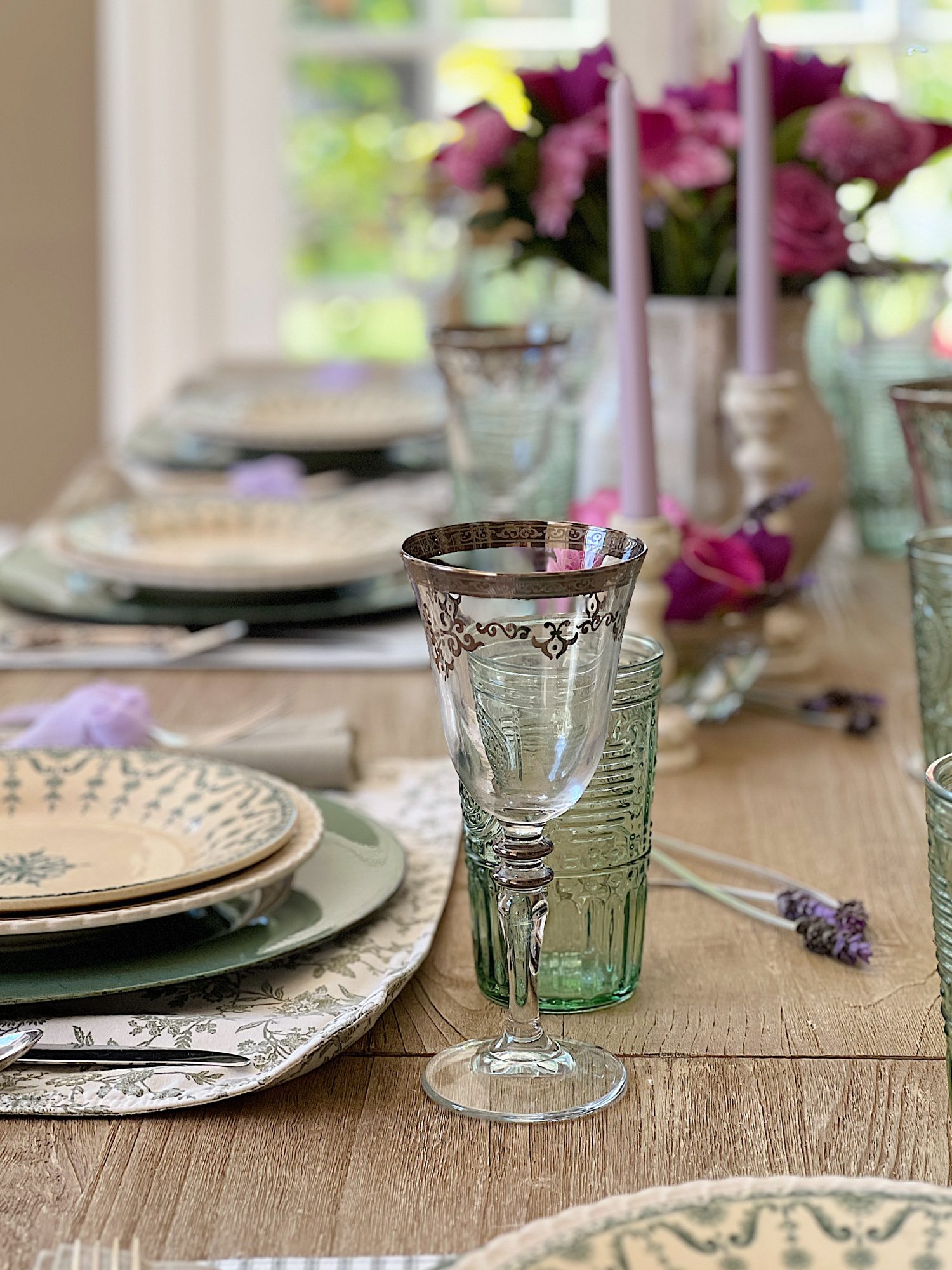 A spring table set in the dining room with green and white plates and napkins, lavender ties, green and sil