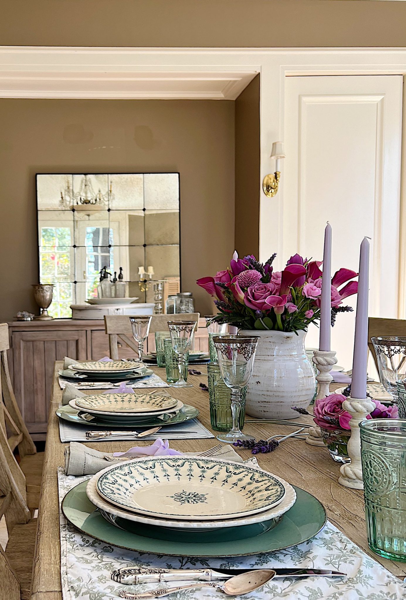 A spring table set in the dining room with green and white plates and napkins, lavender ties, green and sil