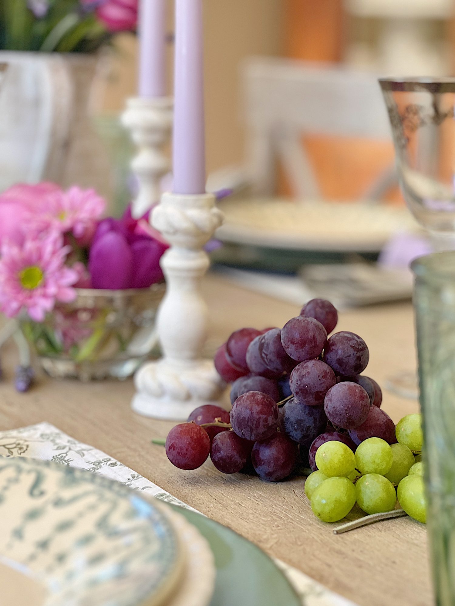 A spring table set in the dining room with green and white plates and napkins, lavender ties, green and sil
