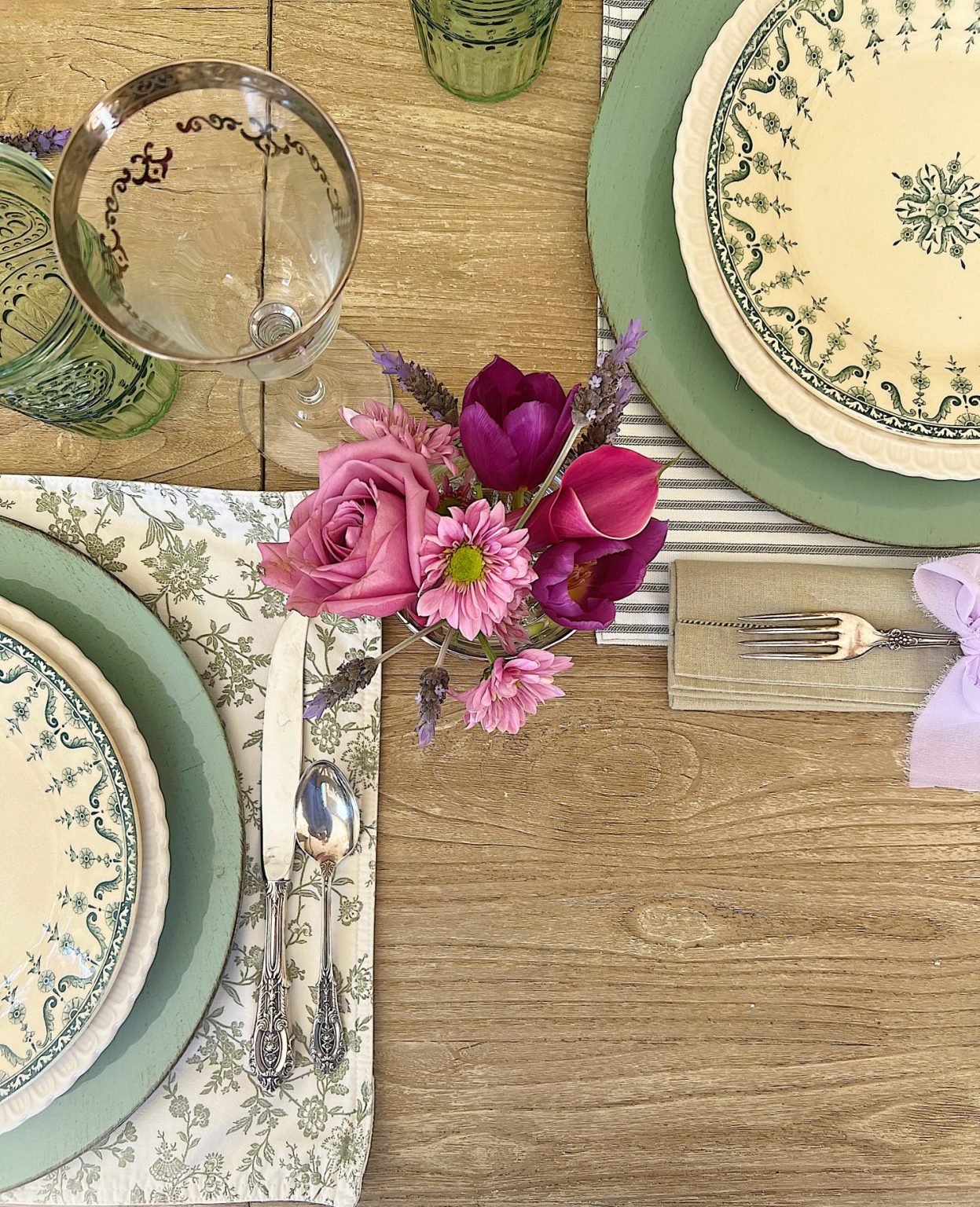 A spring table set in the dining room with green and white plates and napkins, lavender ties, green and sil