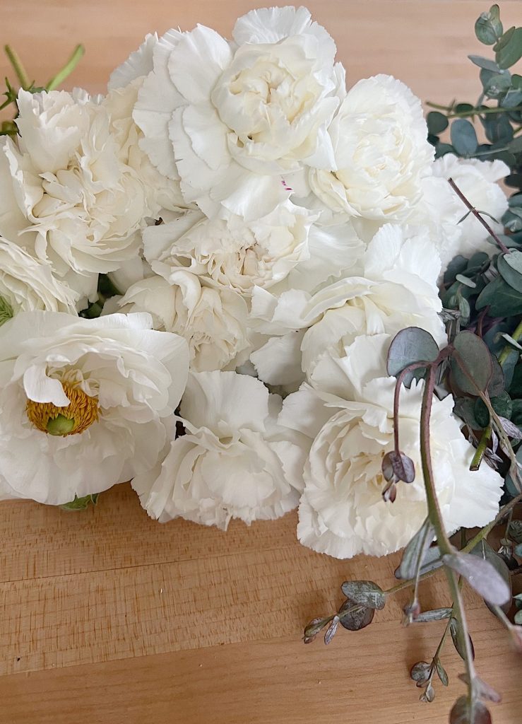 Eucalyptus and white flowers lying on a counter.