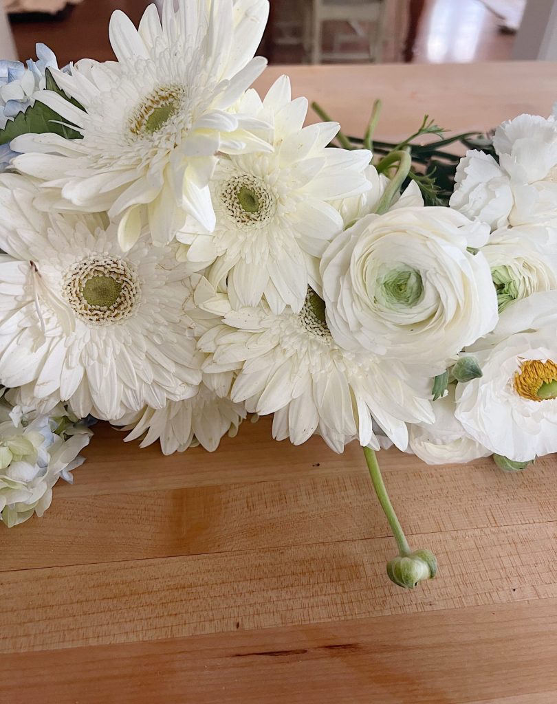 white runanculas and gerbera flowers on a counter
