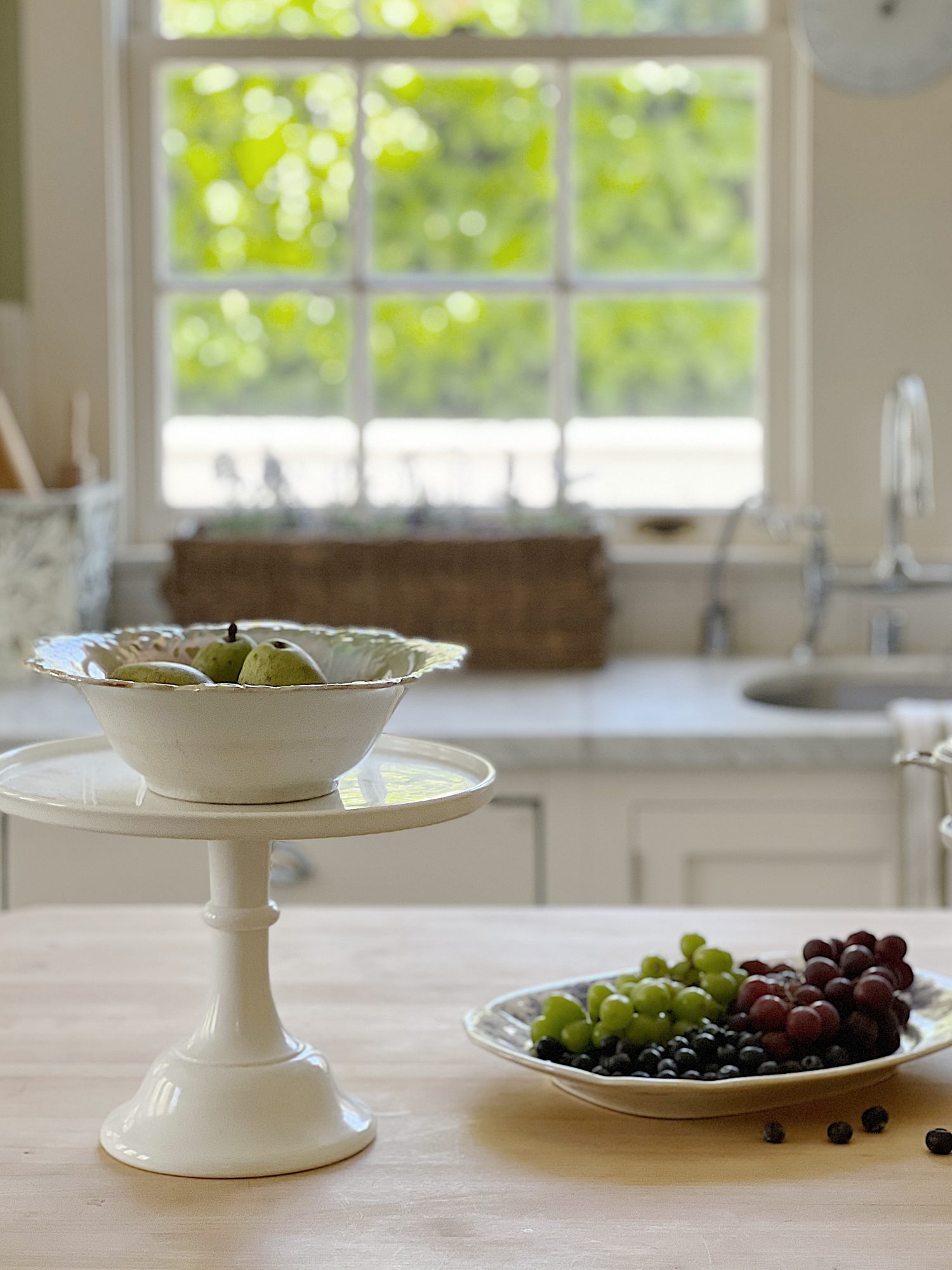 A traditional kitchen with white cabinets and light green walls and white marble countertops decorated with sage green and lavender items for spring.