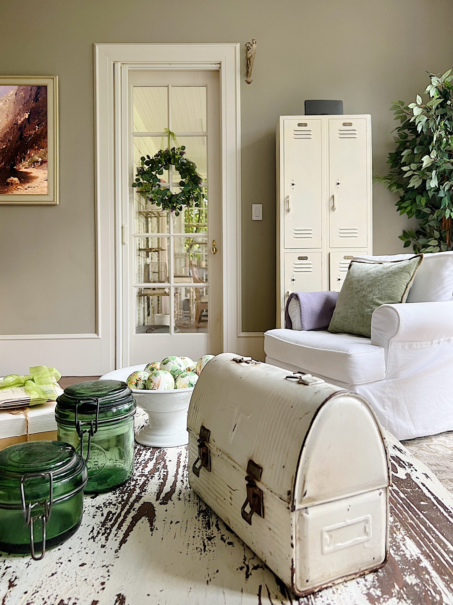 New spring home decor in the family room with lavender throws and pillows and sage green jars, a wreath and small decor items.
