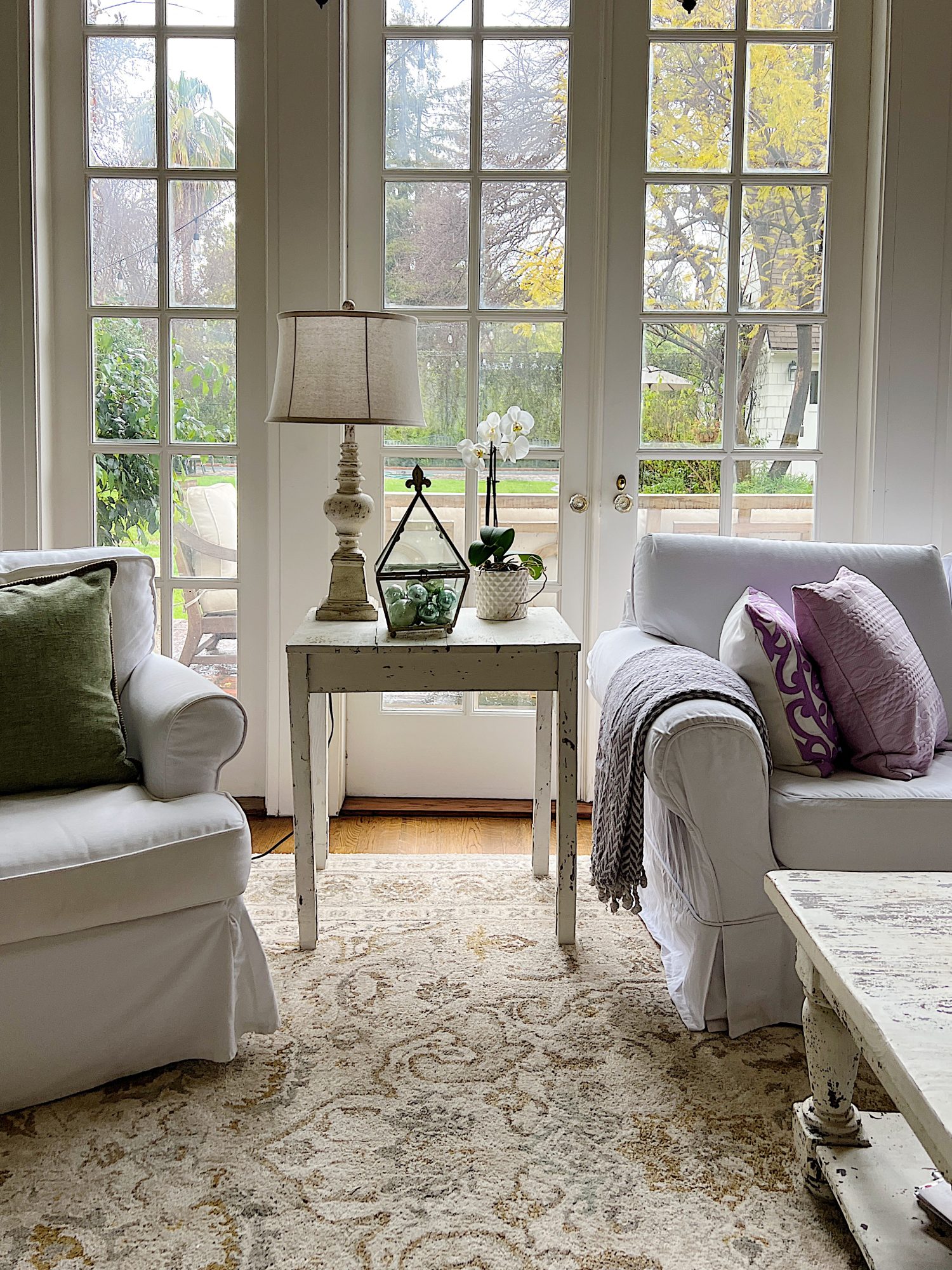 New spring home decor in the family room with lavender throws and pillows and sage green jars, a wreath and small decor items.