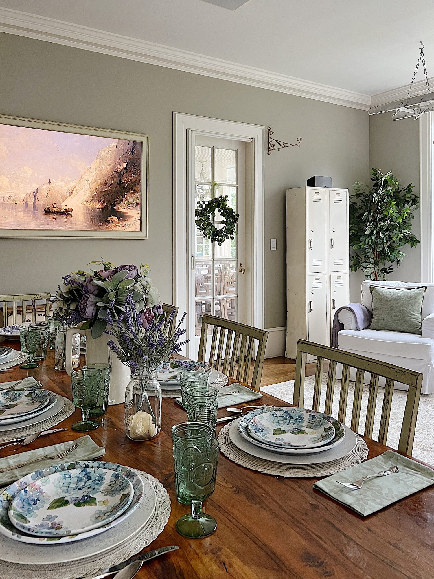 New spring home decor in the family room with lavender throws and pillows and sage green jars, a wreath and small decor items.