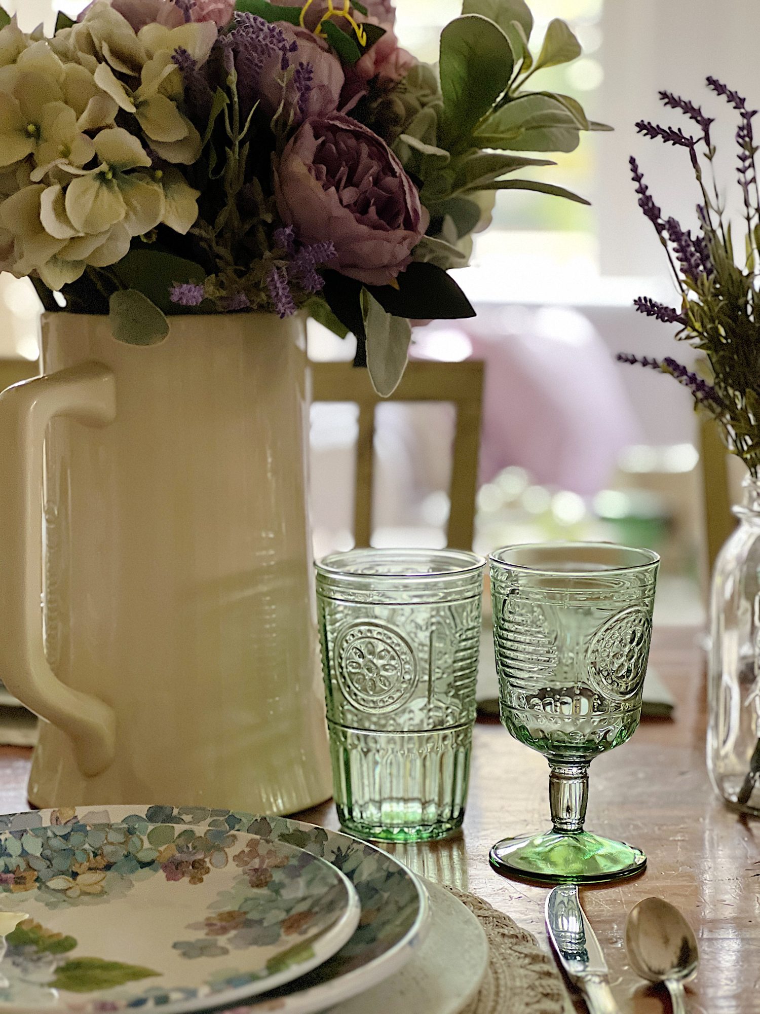 New spring home decor in the family room with lavender throws and pillows and sage green jars, a wreath and small decor items.