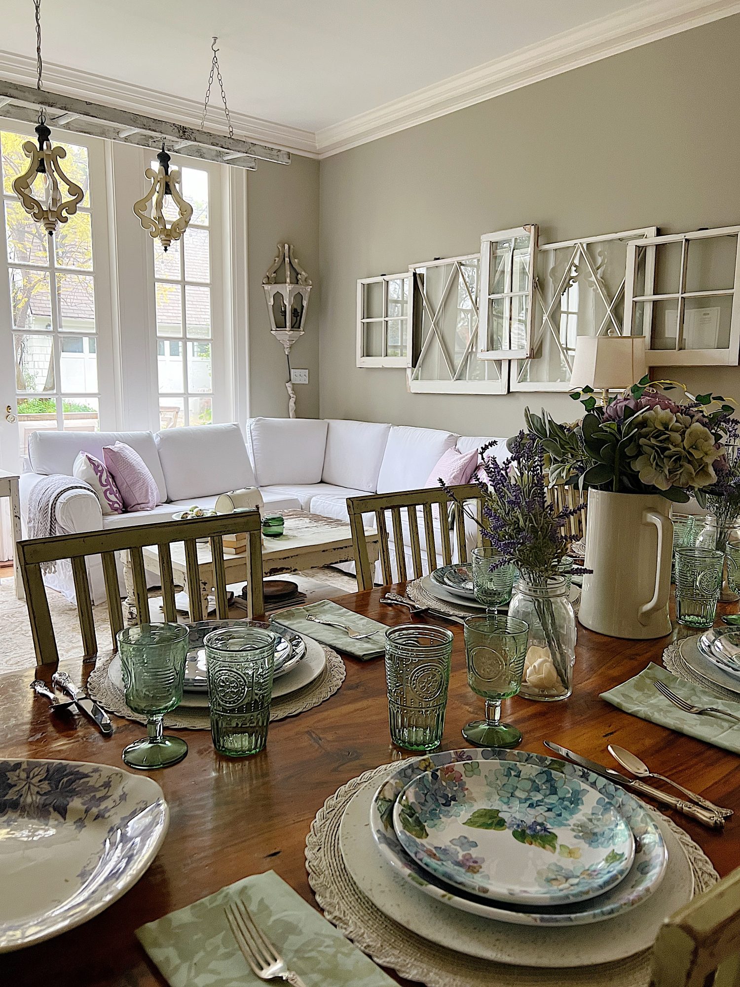 New spring home decor in the family room with lavender throws and pillows and sage green jars, a wreath and small decor items.