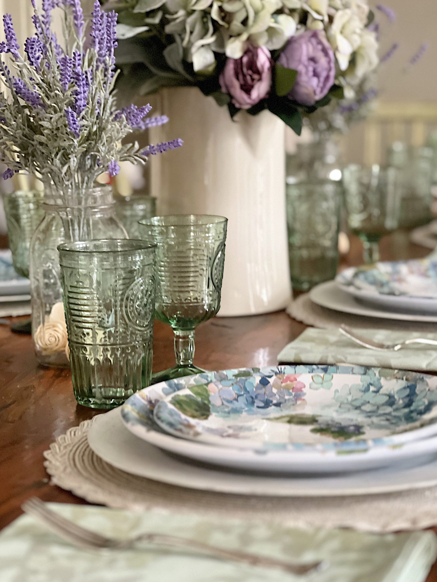 New spring home decor in the family room with lavender throws and pillows and sage green jars, a wreath and small decor items.