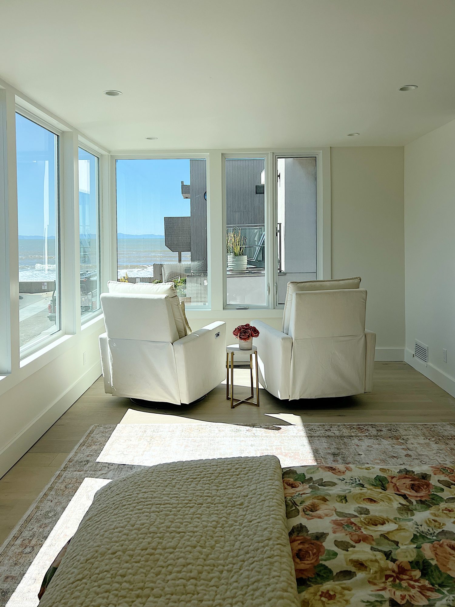 primary bedroom with bed, rug, twho swivel chairs and large windows.
