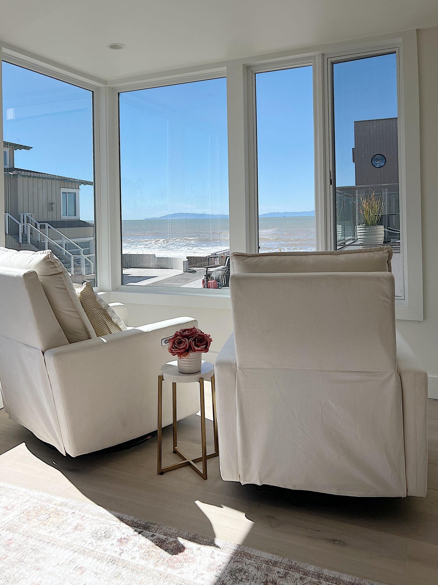 two white swivel chairs with small table in between with pot and pink-orange roses