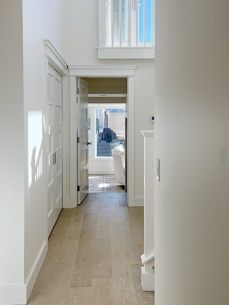 A hallway with light wood floors wchich leads to the primary bedroom.