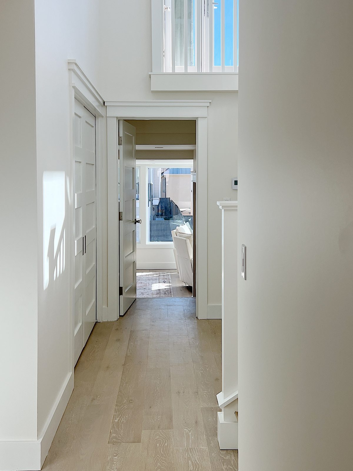 A hallway with light wood floors wchich leads to the primary bedroom.