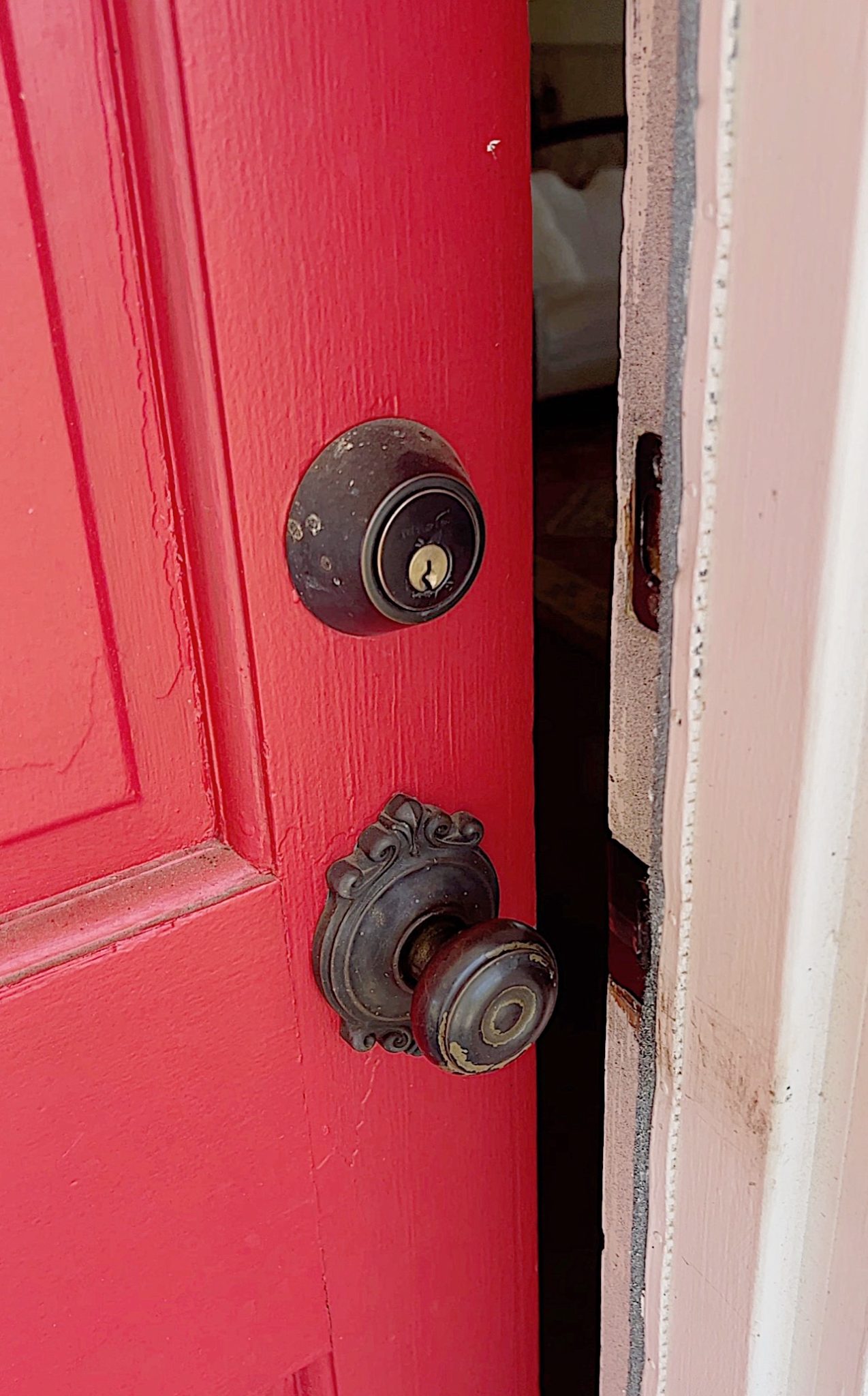 A red door entering a white vintage home.