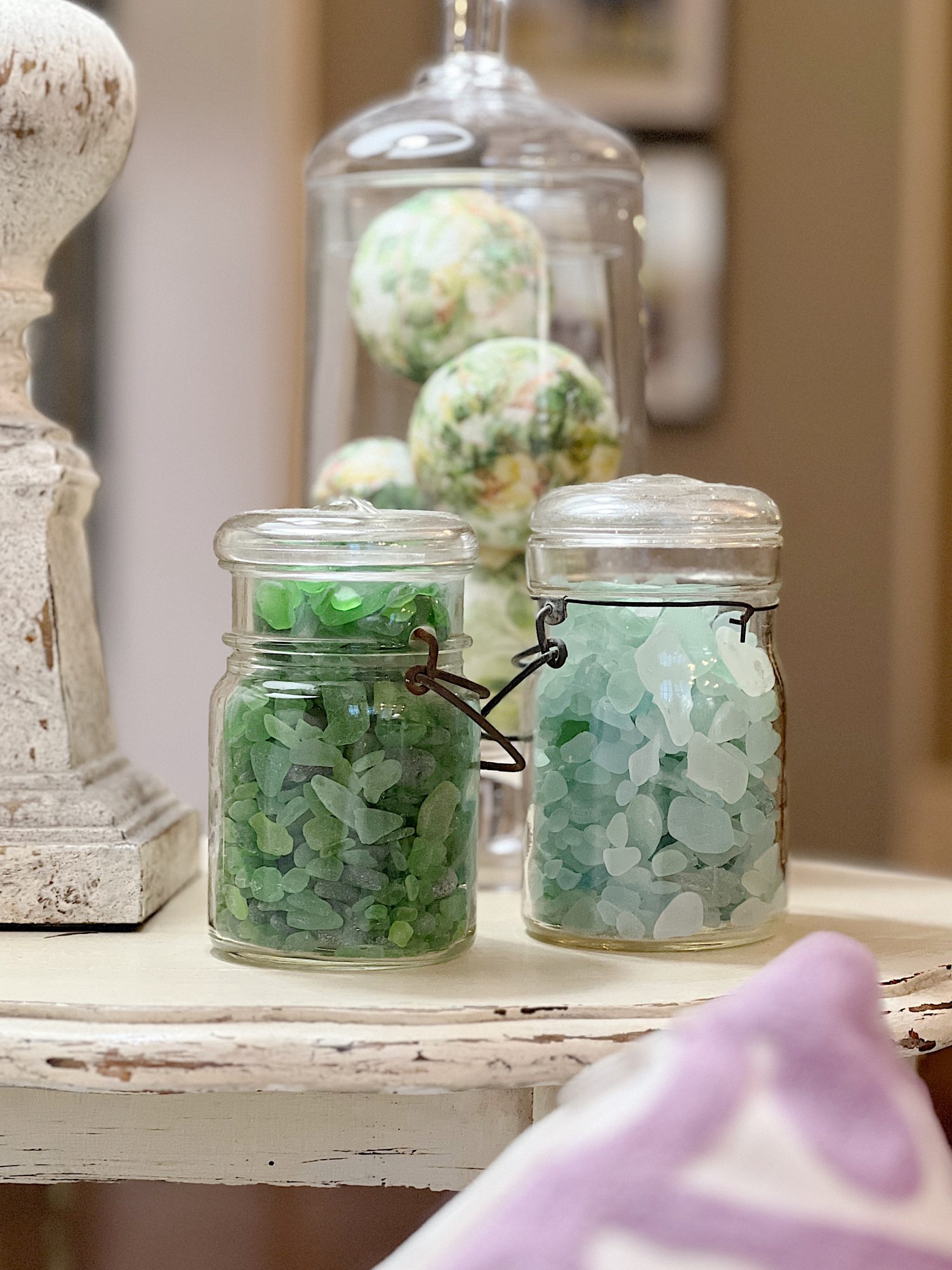 New spring home decor in the family room with lavender throws and pillows and sage green jars, a wreath and small decor items.