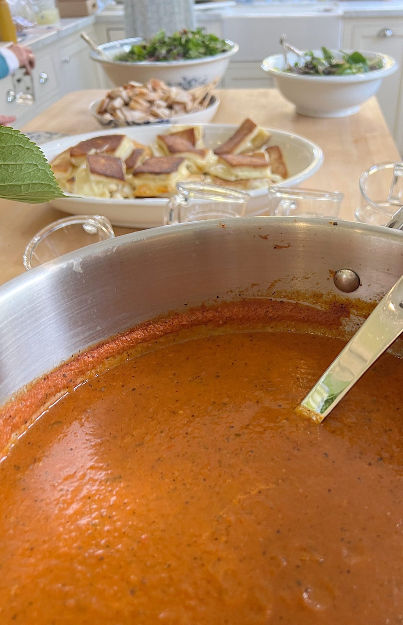 Tomato bisque soup, grilled cheese sandwiches, and chicken salad buffet on the kitchen island.