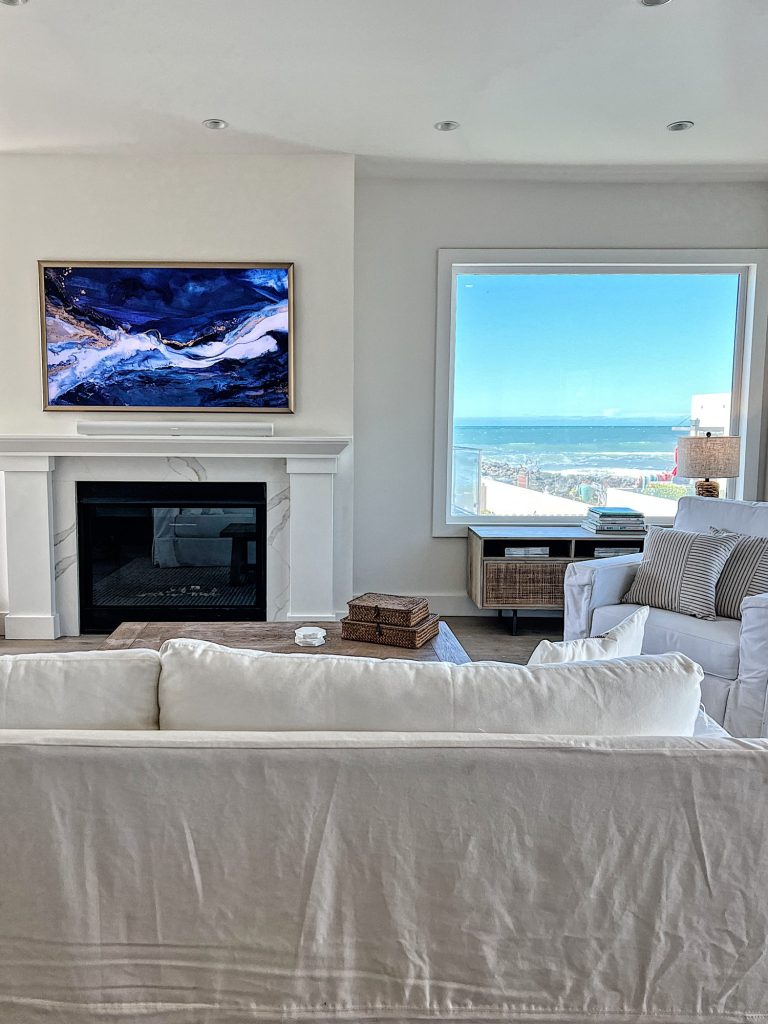 Beach house living room with farmhouse style furniture and large fireplace and frame tv.