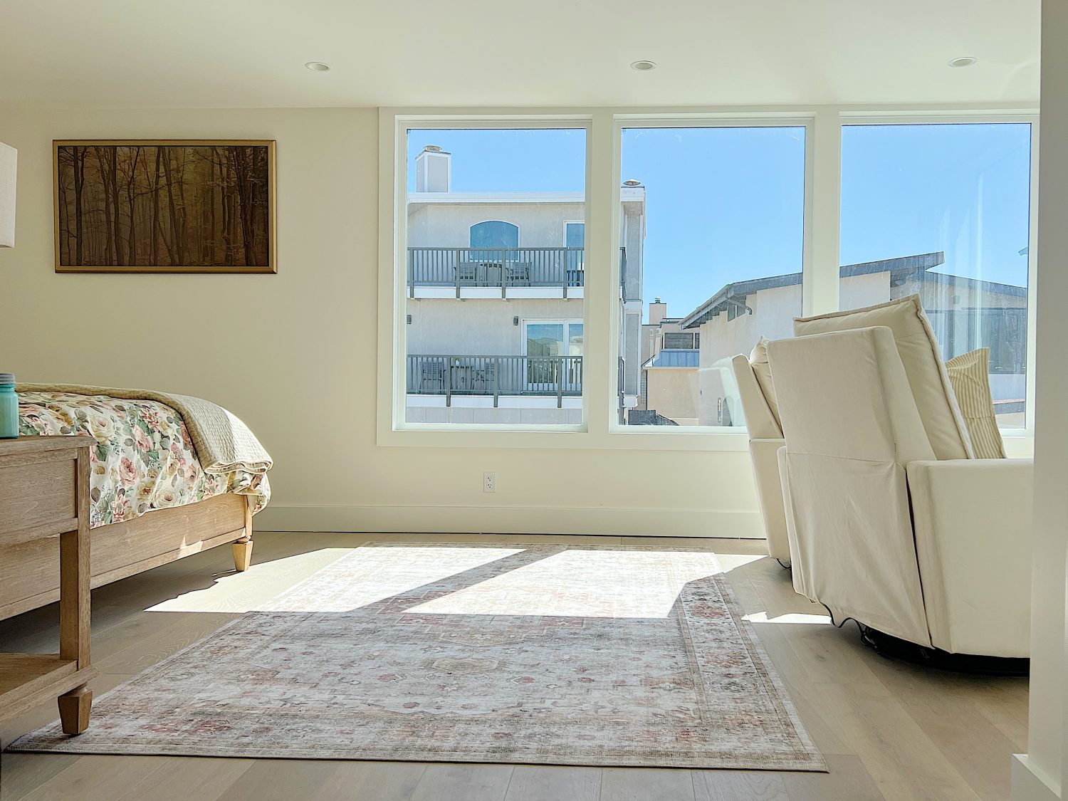 the primary bedroom with a wood bed, two swivel chairs and a new rug