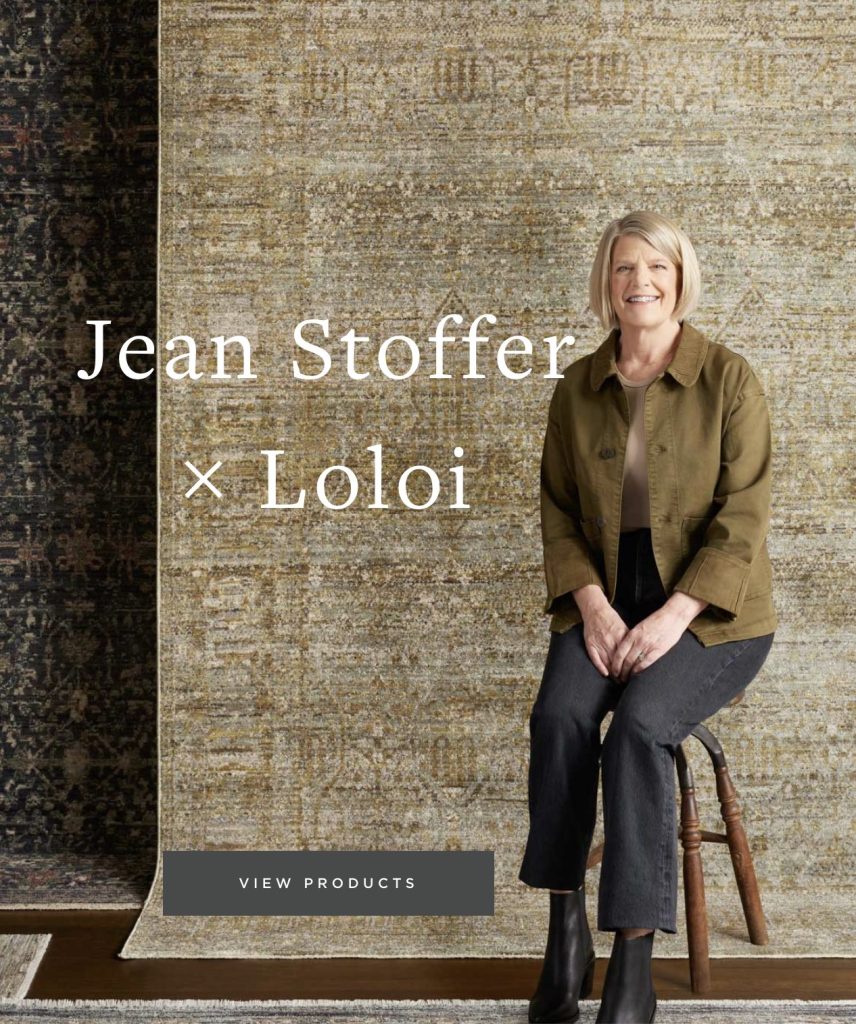 Interior designer Jean Stoffer sitting on a stool in front of her new rug collection with Loloi rugs