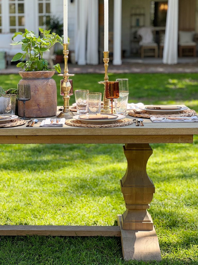 Earth Day dinner with Arhaus table, chairs, plates, colored glassware, salmon salad, copper silverware, and large stoneware vases with live tomato plants.