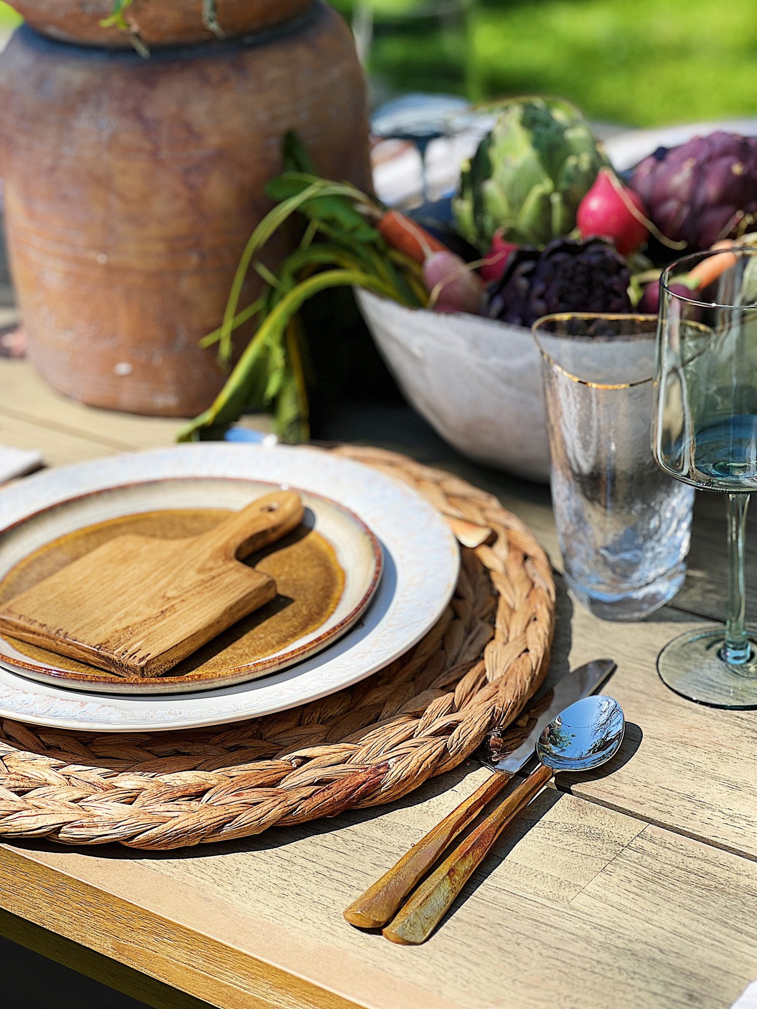 Earth Day dinner with Arhaus table, chairs, plates, colored glassware, salmon salad, copper silverware, and large stoneware vases with live tomato plants.