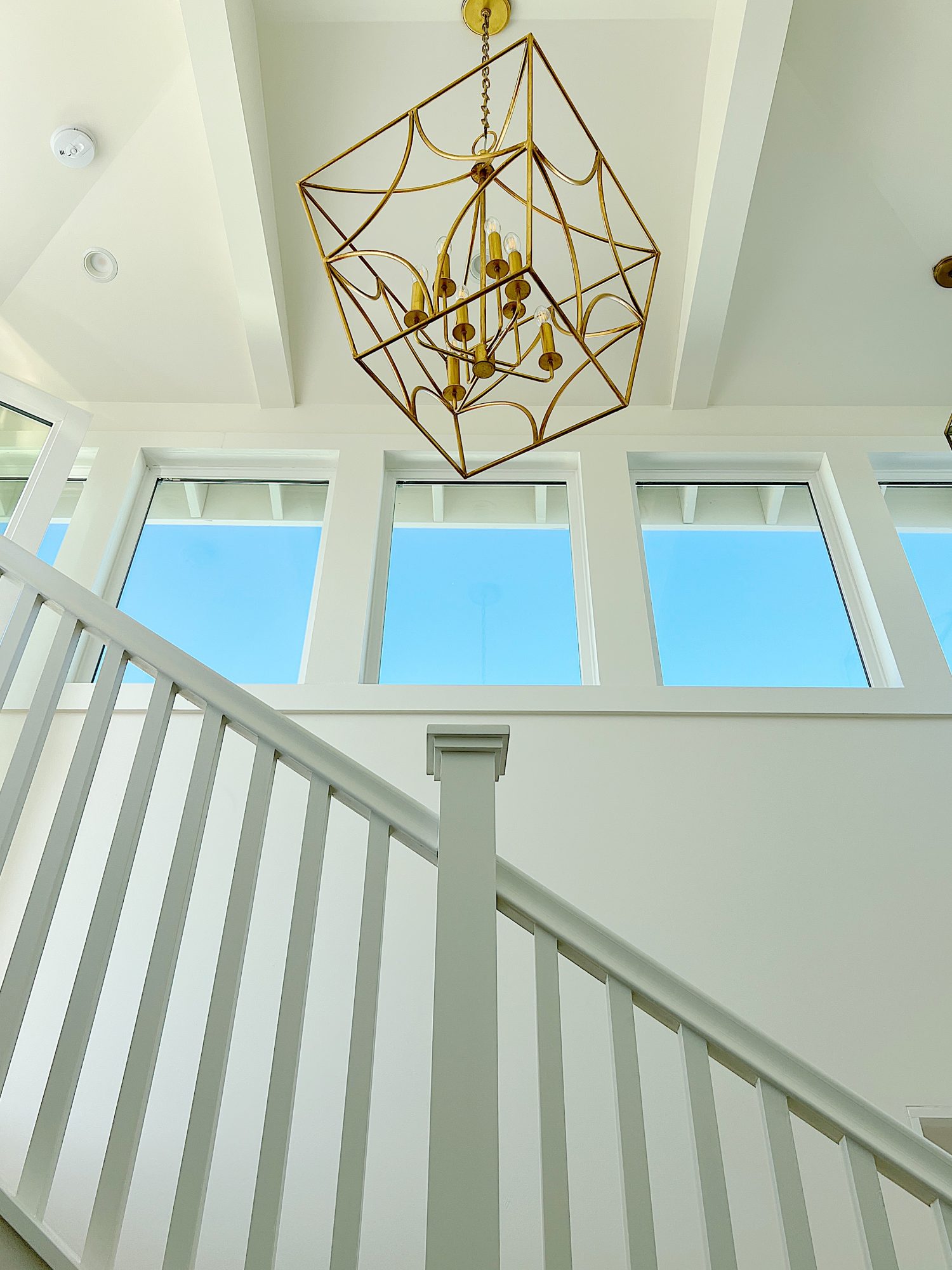 A large brass pendant hanging above a third-floor staircase.