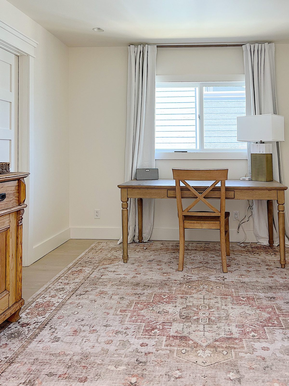A gold and marble lamp sitting on a desk in an office with a chair, rug, and cabinet.