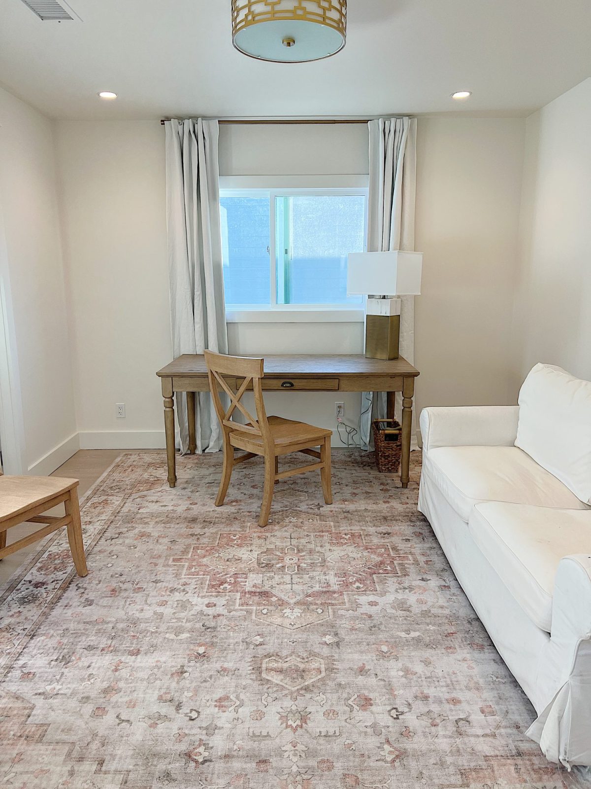 A gold and marble lamp sitting on a desk in an office with a chair, rug, and cabinet.