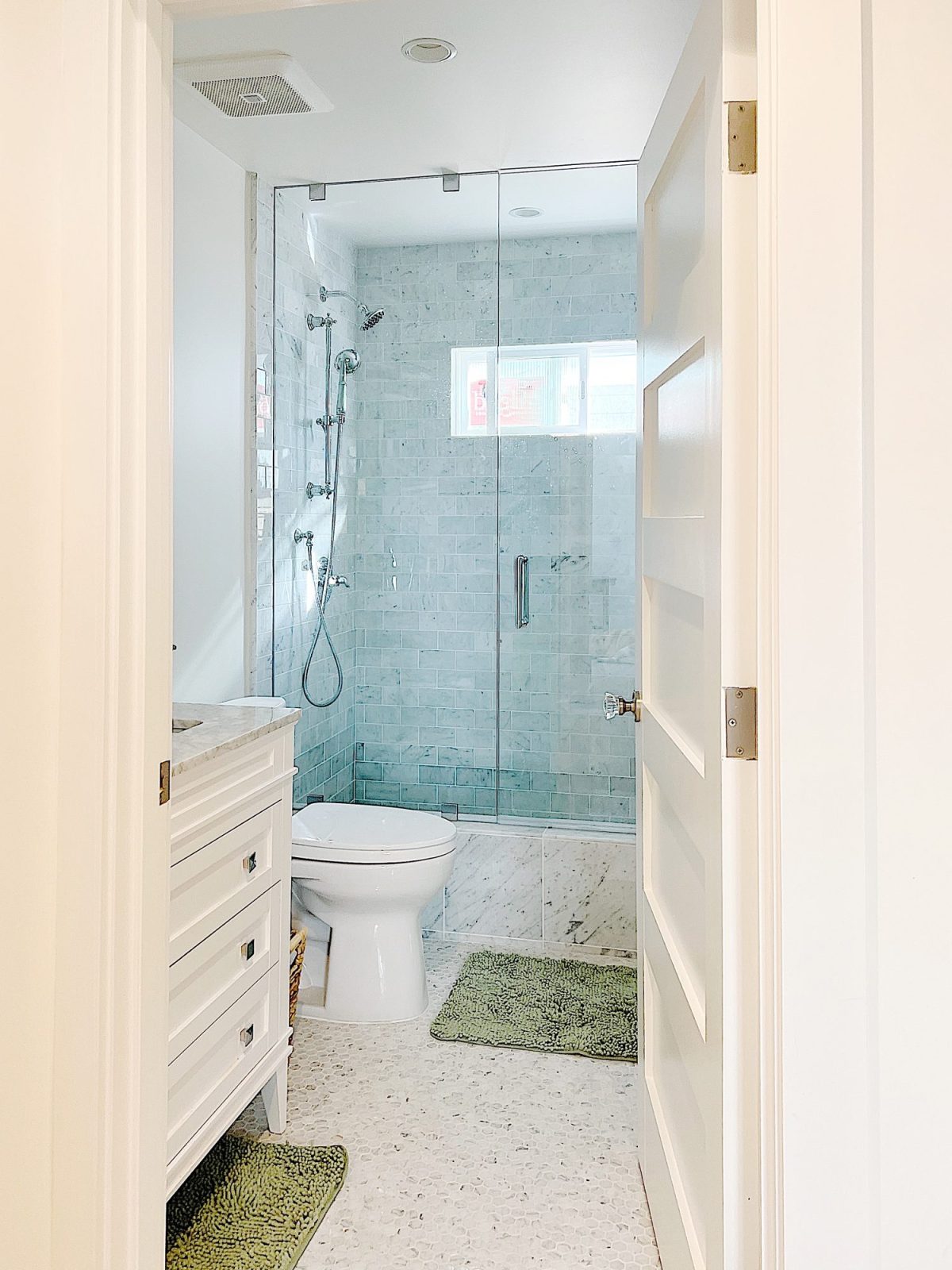A bathroom mirror, sink with marble countertop and chrome fixtures.