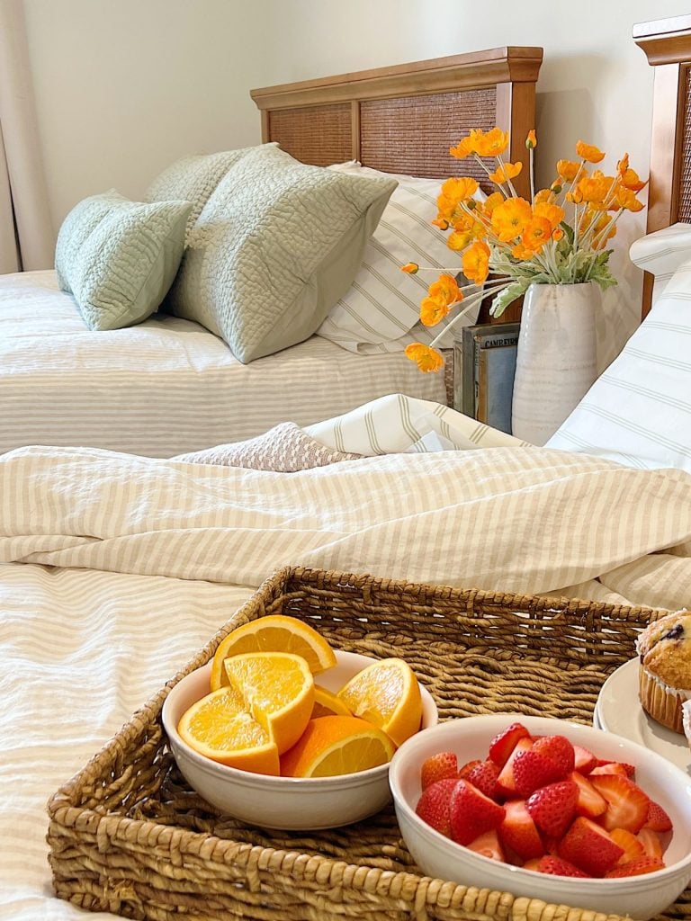 Green pillows on a bed with a tray of breakfast items.